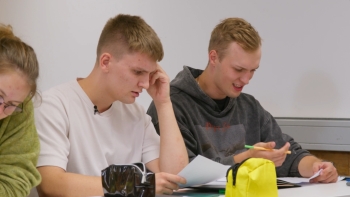 Auf dem Foto sind zwei Schüler zu sehen, die an einem Tisch zusammensitzen.